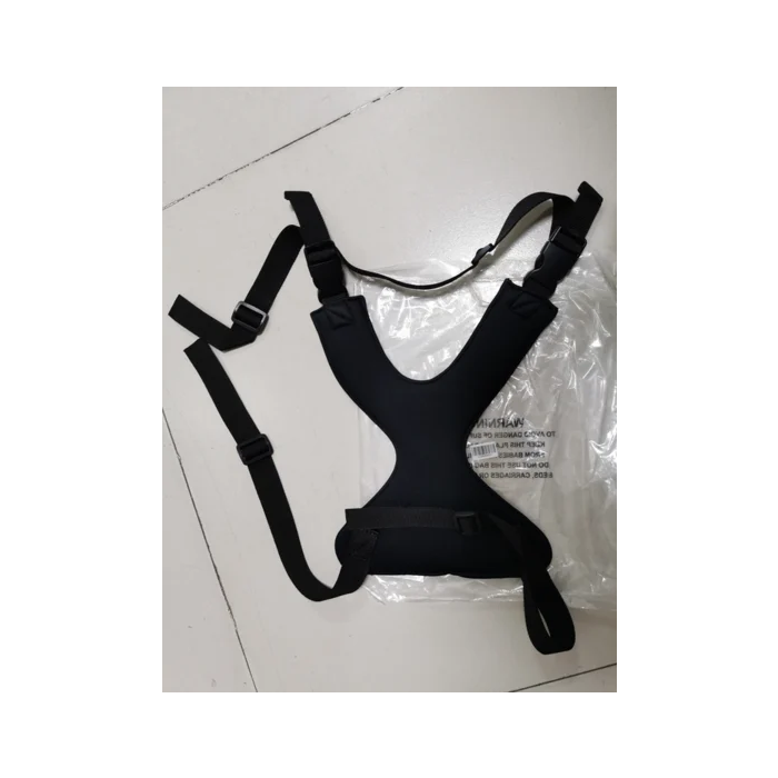 Black harness on a white floor with a clear plastic bag underneath